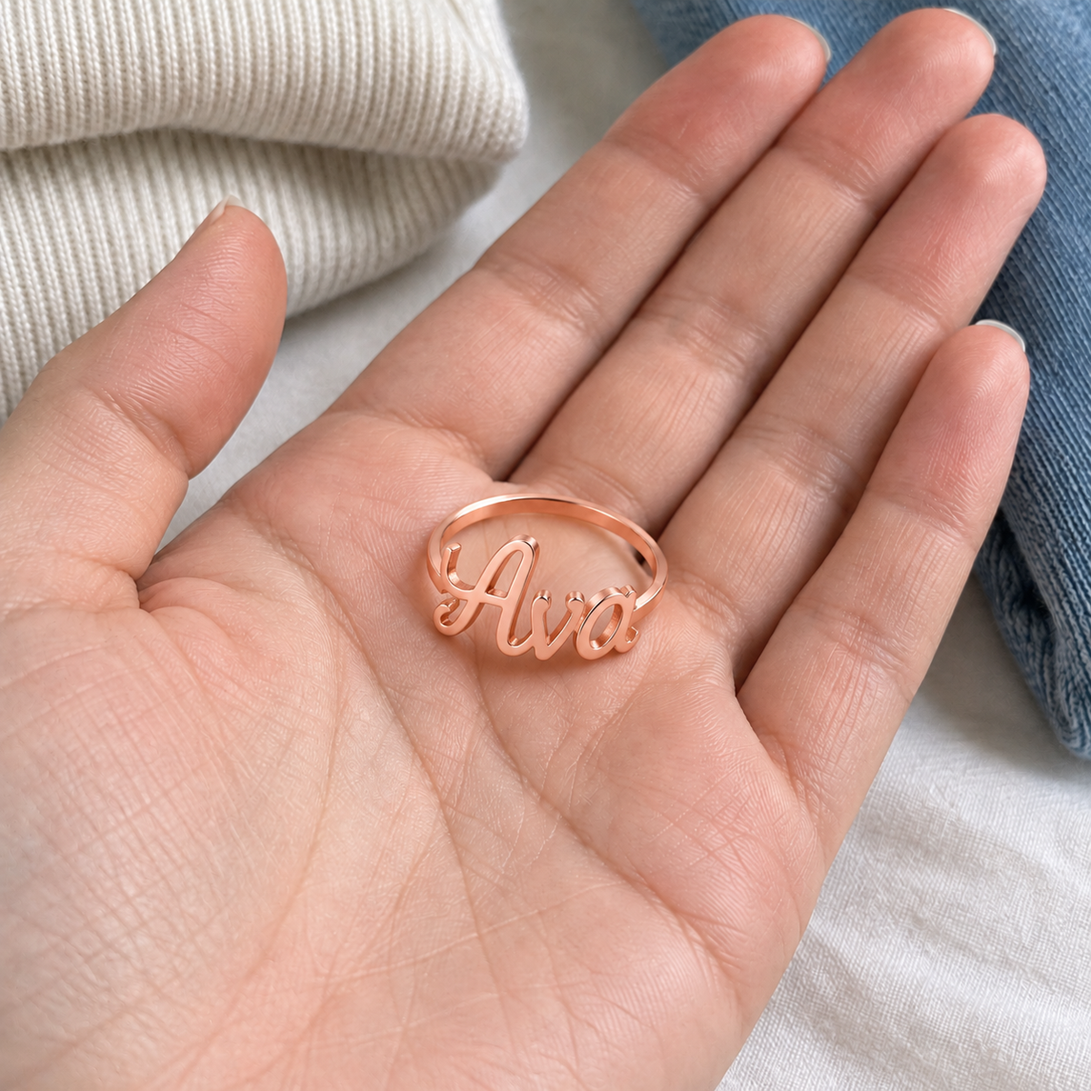 Custom Script Name Ring in rose gold with Ava personalization, casual phone-style view resting in an open palm - Anthology Jewelry
