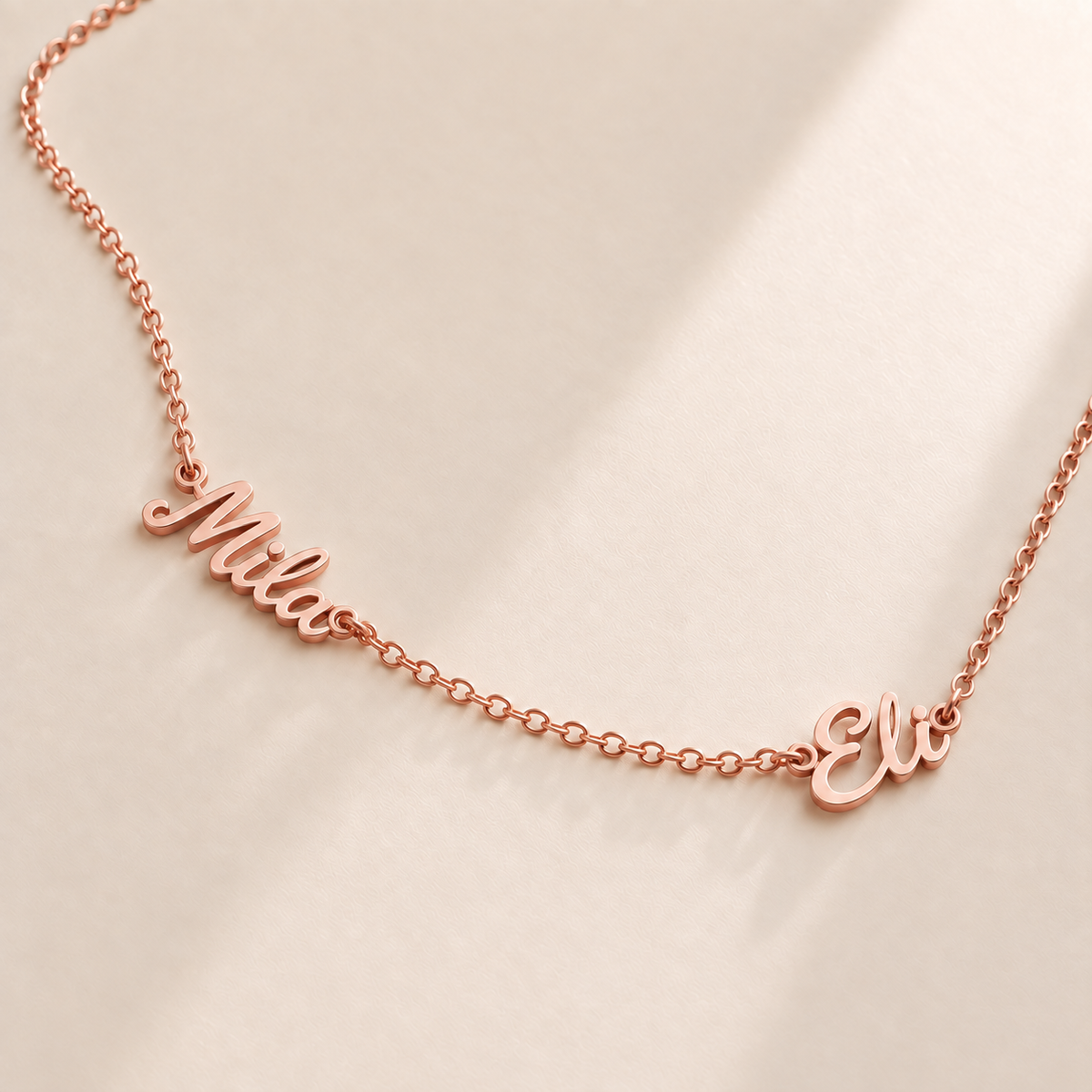 Custom Spaced Names Necklace hero photo - two connected script names on a rose gold rolo chain Anthology Jewelry