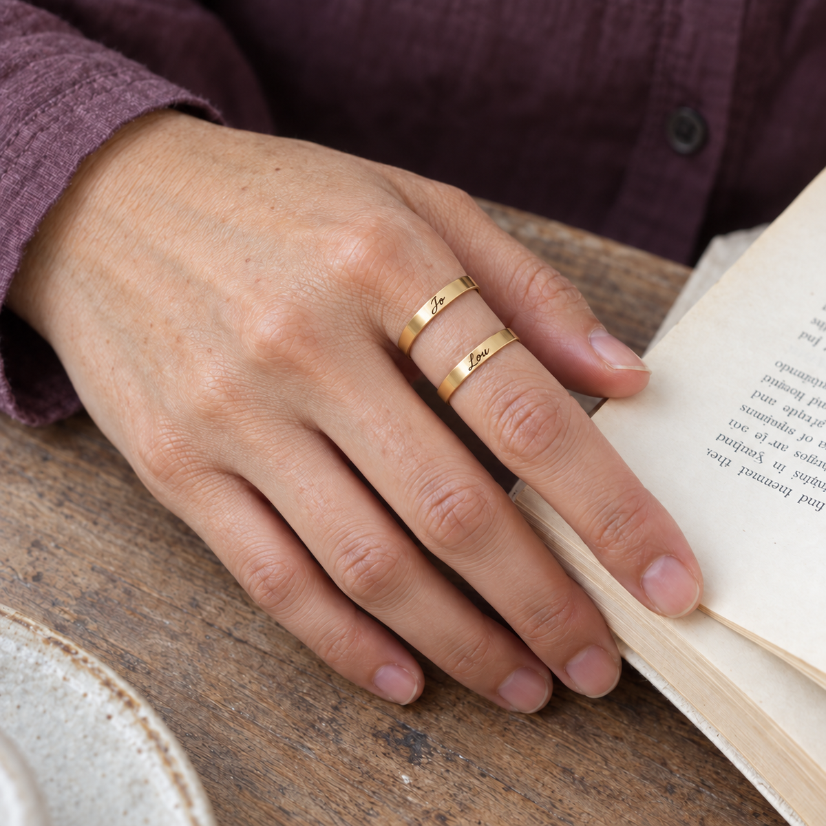 Custom Thin Double Ring lifestyle photo - hand on an open paperback wearing gold double band ring Anthology Jewelry