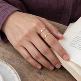 Custom Thin Double Ring lifestyle photo - hand on an open paperback wearing gold double band ring Anthology Jewelry