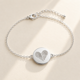 Custom Two Fingerprint Heart Bracelet hero photo - silver engraved disc bracelet on cream background Anthology Jewelry
