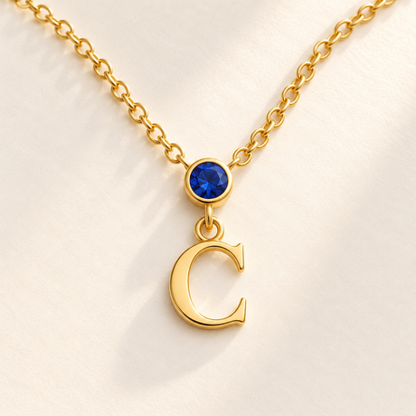 Custom Vertical Birthstone Initial Necklace macro detail photo - complete gold serif C pendant with September blue round gemstone and bezel Anthology Jewelry