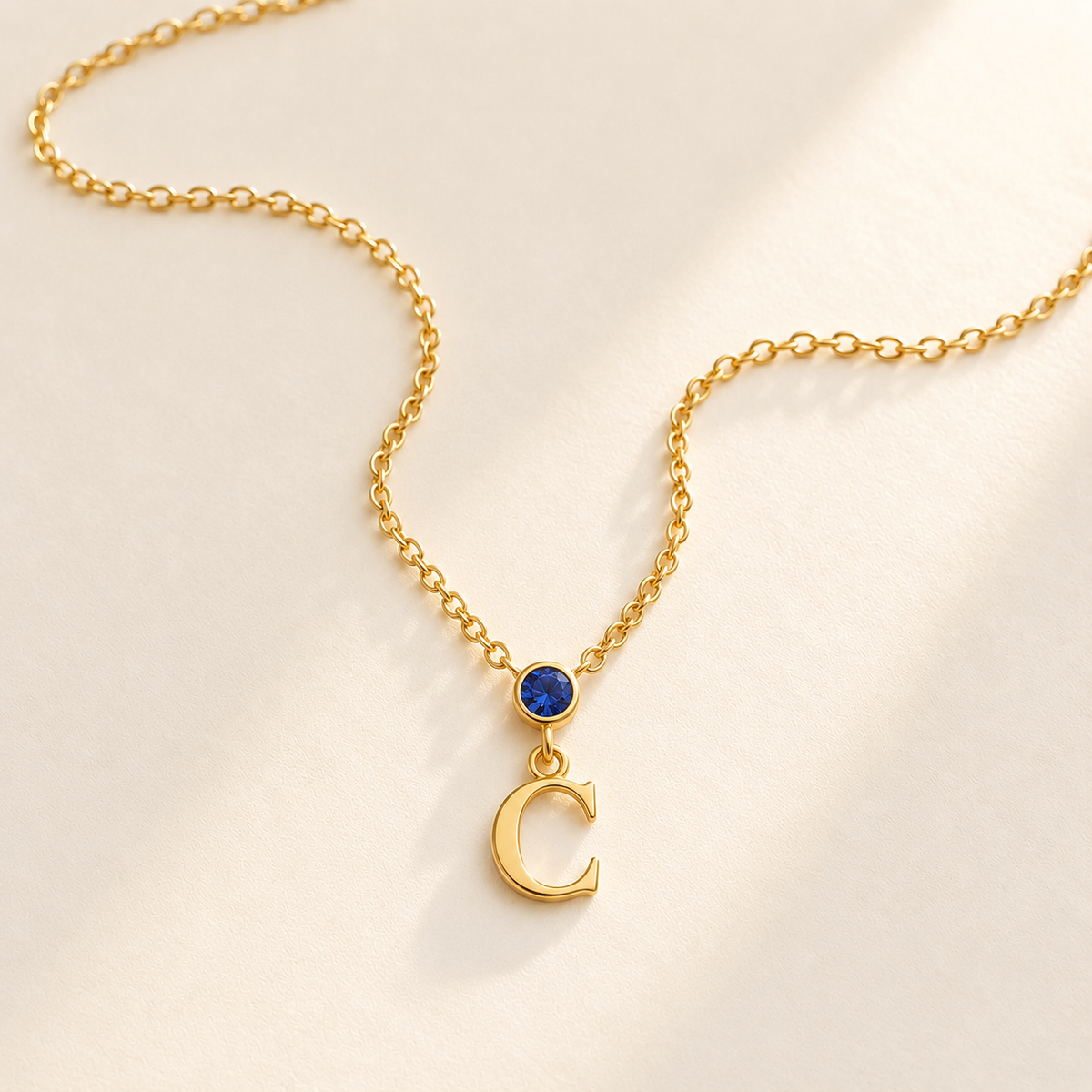 Gold vertical birthstone initial necklace with blue September stone and C initial