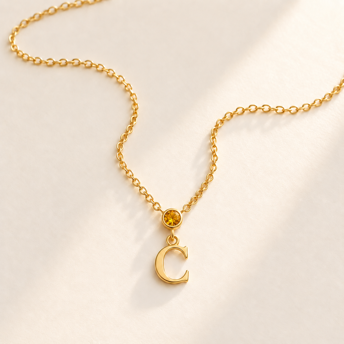 Gold vertical initial necklace with november birthstone-color center stone