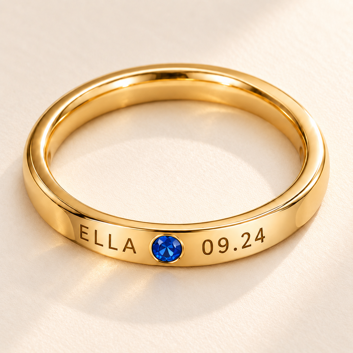 Custom Date & Name Birthstone Stacking Ring detail macro photo - gold ring with ELLA and 09.24 beside a blue birthstone Anthology Jewelry