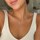 "Love" Necklace detail photo - alternate angle of polished gold script lettering Anthology Jewelry