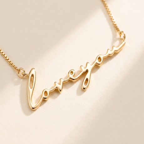 "Loveyou" Necklace detail photo - close-up of polished gold script lettering Anthology Jewelry