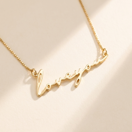 "Loveyou" Necklace hero photo - gold script cutout pendant on cream background Anthology Jewelry